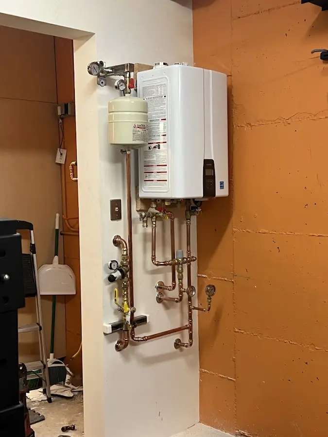 Plumbing technician inspecting water heater connections in Fridley